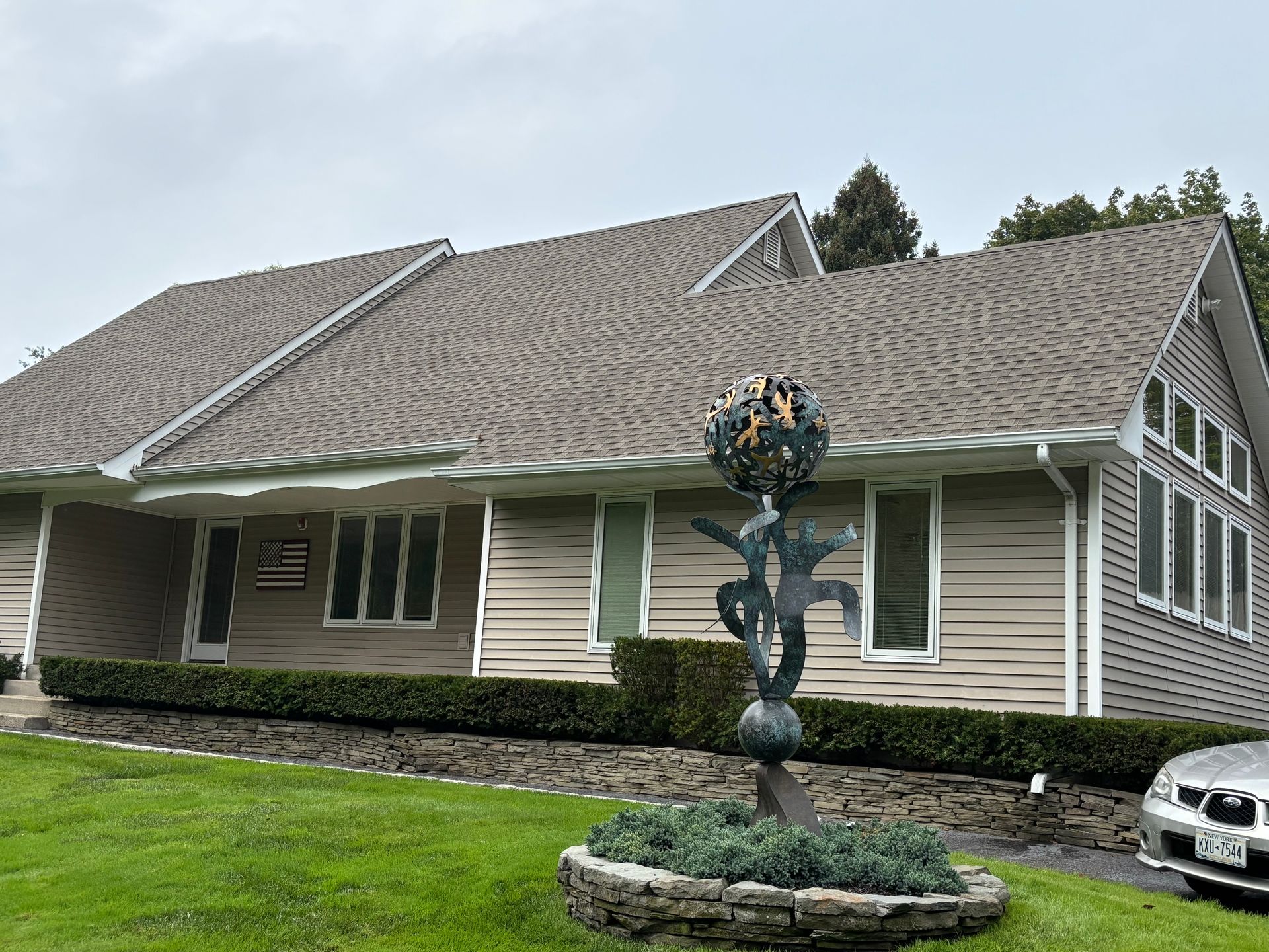 Tan building with a dark roof and sculptural metal art in front