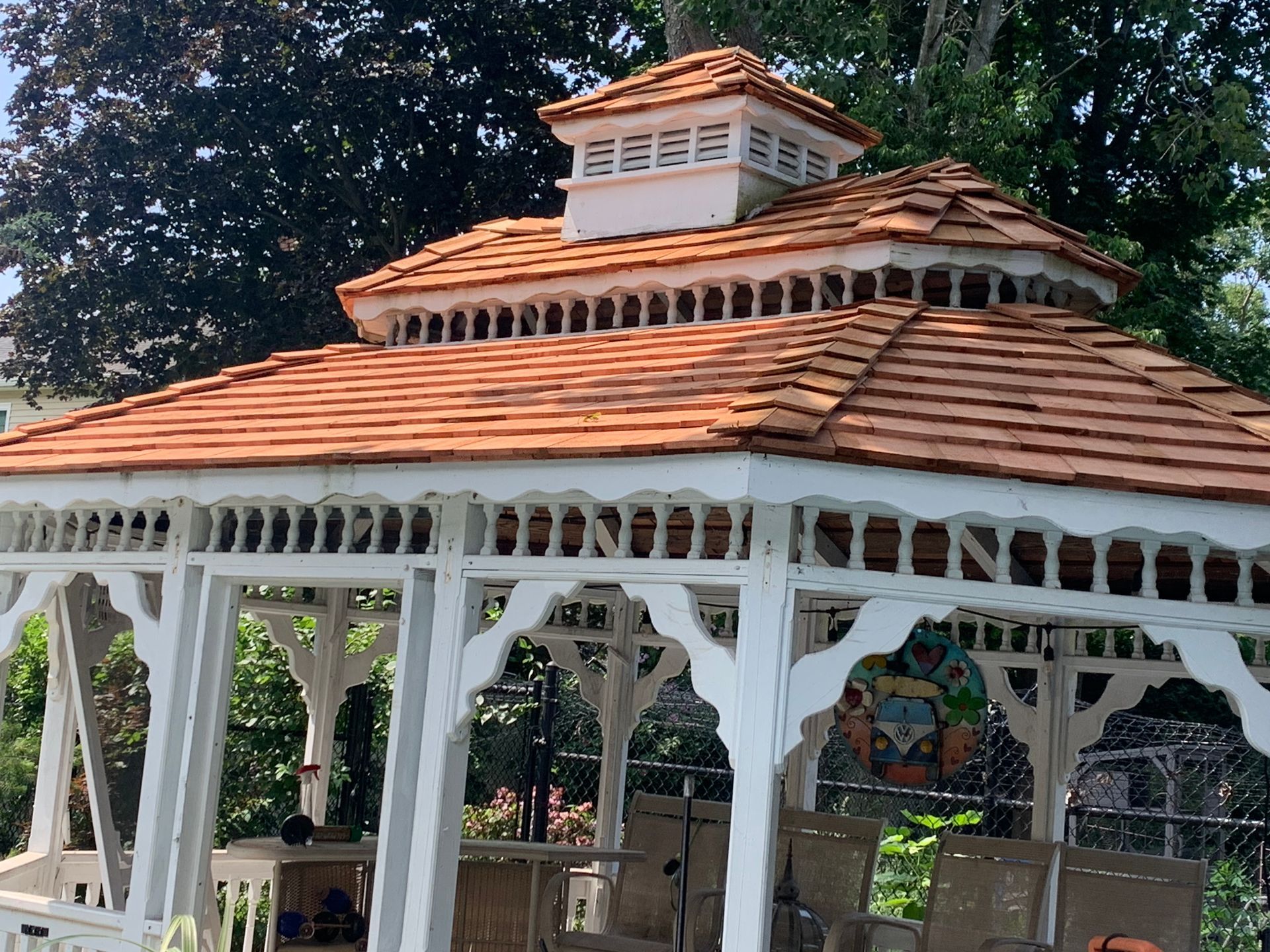 White gazebo with a reddish-brown shingled roof and a white cupola