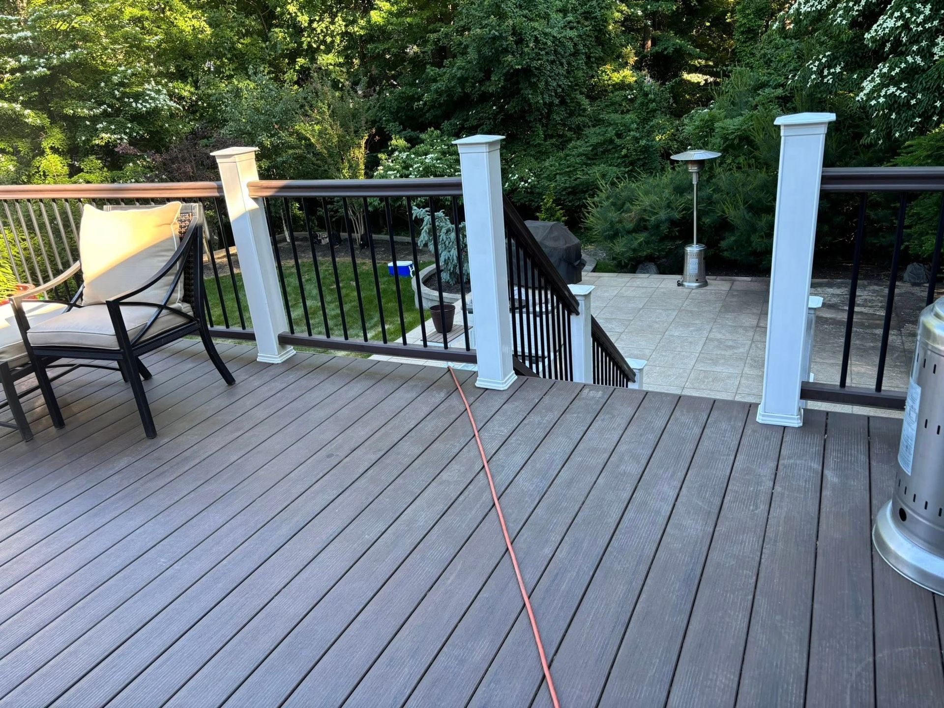Back deck with white posts, black railings, and patio chairs