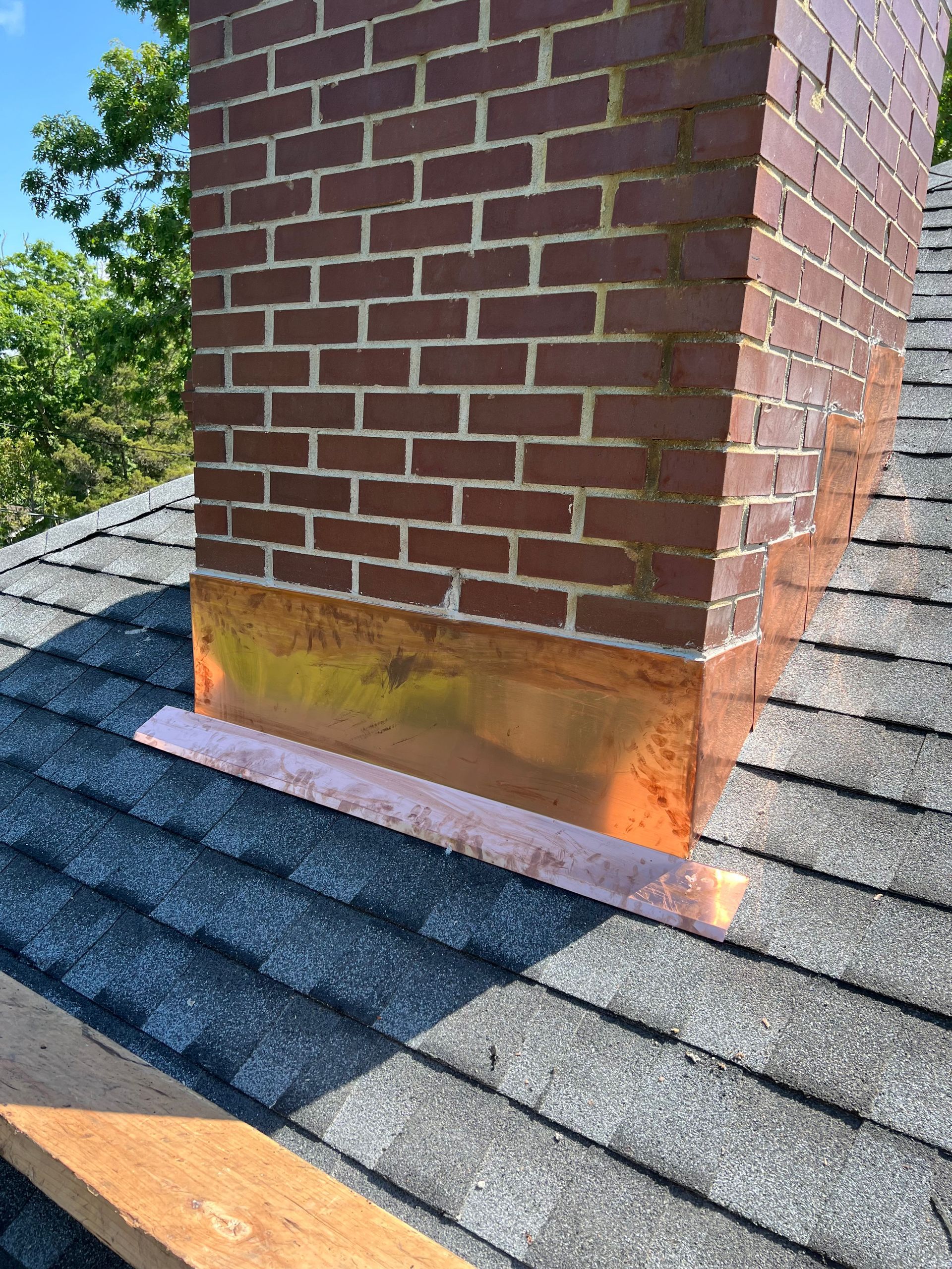 Brick chimney with copper flashing on a shingled roof