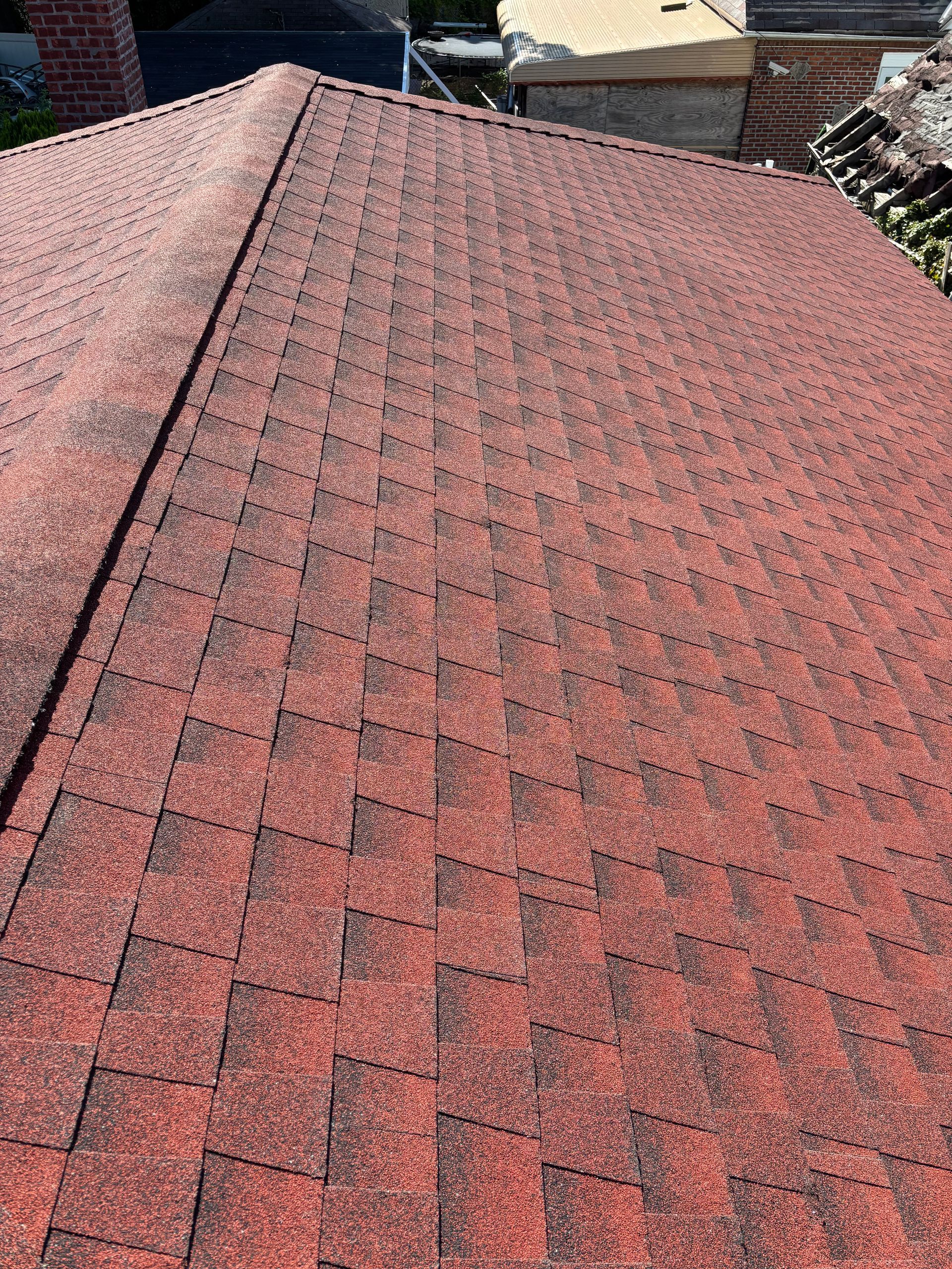 Red asphalt shingle roof with a prominent ridge line and brick chimney